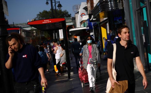 Dos hombres caminan este lunes por el centro de Londres sin mascarilla.