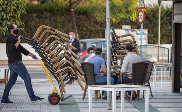 Un trabajador de un bar retira las sillas de una terraza 