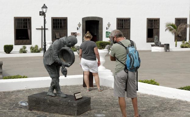 Turistas la semana pasada en Costa Teguise, en Lanzarote. Son muy pocos los visitantes que viajan a Canarias. / CARRASCO