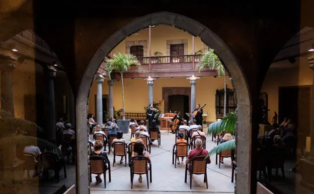 Varias personas disfrutan de una actuación del grupo El Afecto Ilustrado en la Casa de Colón/