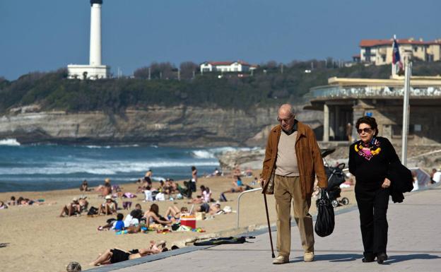 Dos jubilados pasean junto a una playa. 