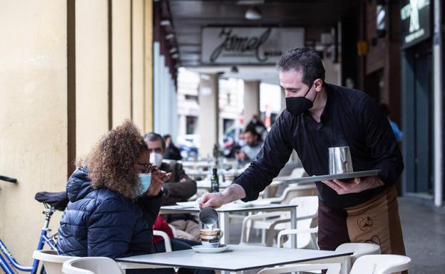 Un camarero sirve un café en una terraza. 