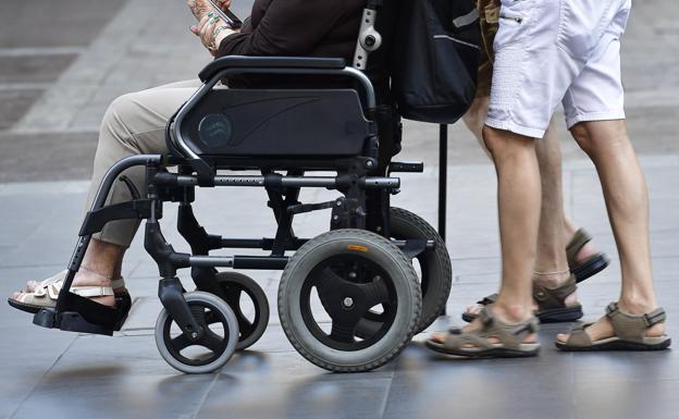 Imagen de archivo de una persona en una silla de ruedas guiada por otra. / JUAN CARLOS ALONSO