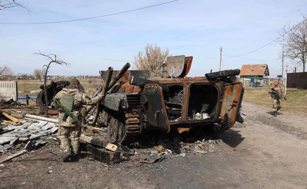Un soldado ucaniano examina los restos de un blindado ruso, destruido al norte de Kiev./AFP