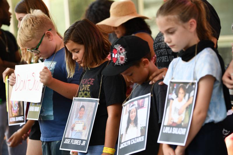 Niños con fotografías de las víctimas del tiroteo en Uvalde participan en un minuto de silencio frente a la Asociación Nacional del Rifle.