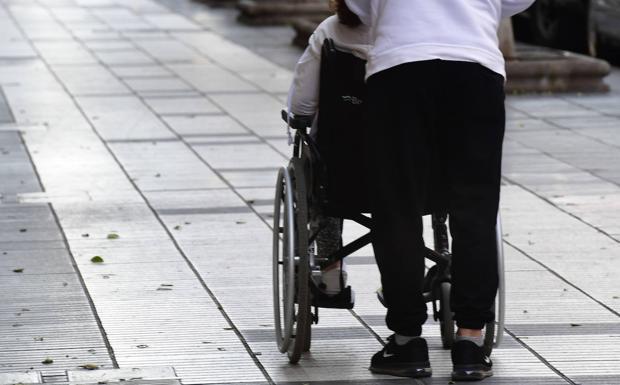 Stock image of a person pushing a dependent's wheelchair. 