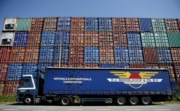 Un camión espera frente a los contenedores de mercancías en el puerto de  Rotterdam. /Reuters
