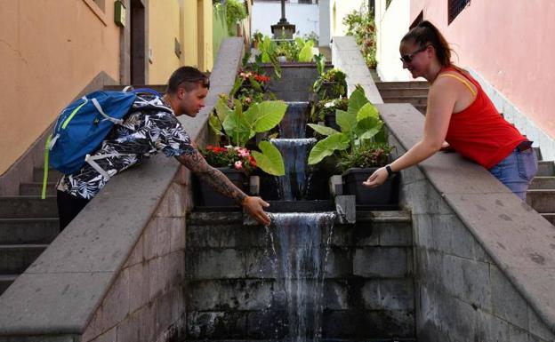 Dos jóvenes combaten el calor mojándose en una fuente de agua de Teror. /Arcadio Suárez