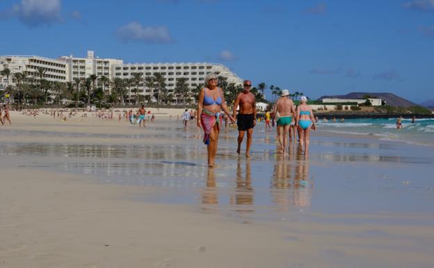 Turistas en las Grandes Playas de Corralejo, con el hotel Tres Islas al fondo. 