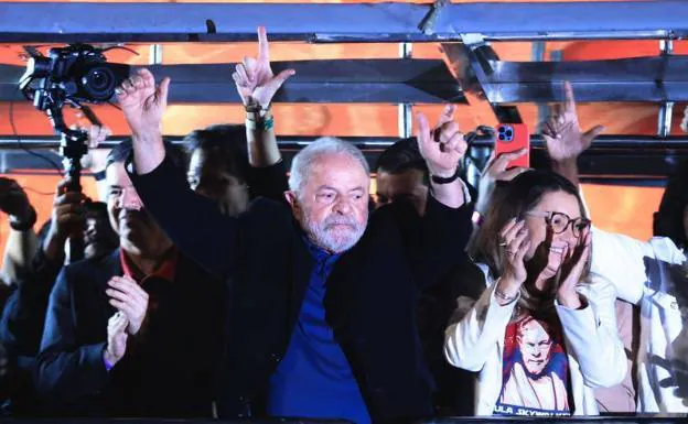 Lula celebra sus resultados ante simpatizantes en la Avenida Paulista de Sao Paulo acompañado de su esposa, Rosangela da Silva. Detrás, miembros de su equipo gesticulan haciendo una 'L' con las manos, símbolo de Lula./Ettore Chiereguini / EFE