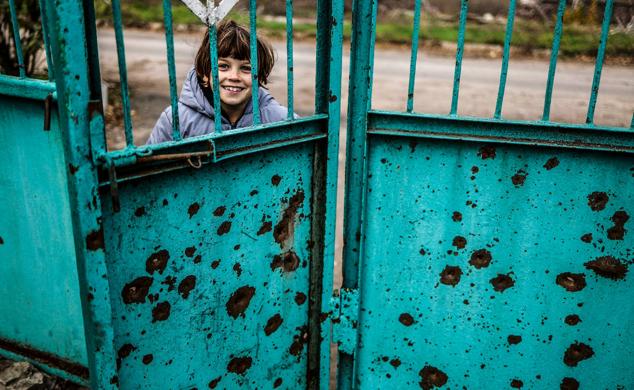 Eva sonríe tras una puerta dañada por la metralla durante los ataques militares rusos en el pueblo de Osokorivka, en la región de Jersón, 9 de noviembre de 2022.